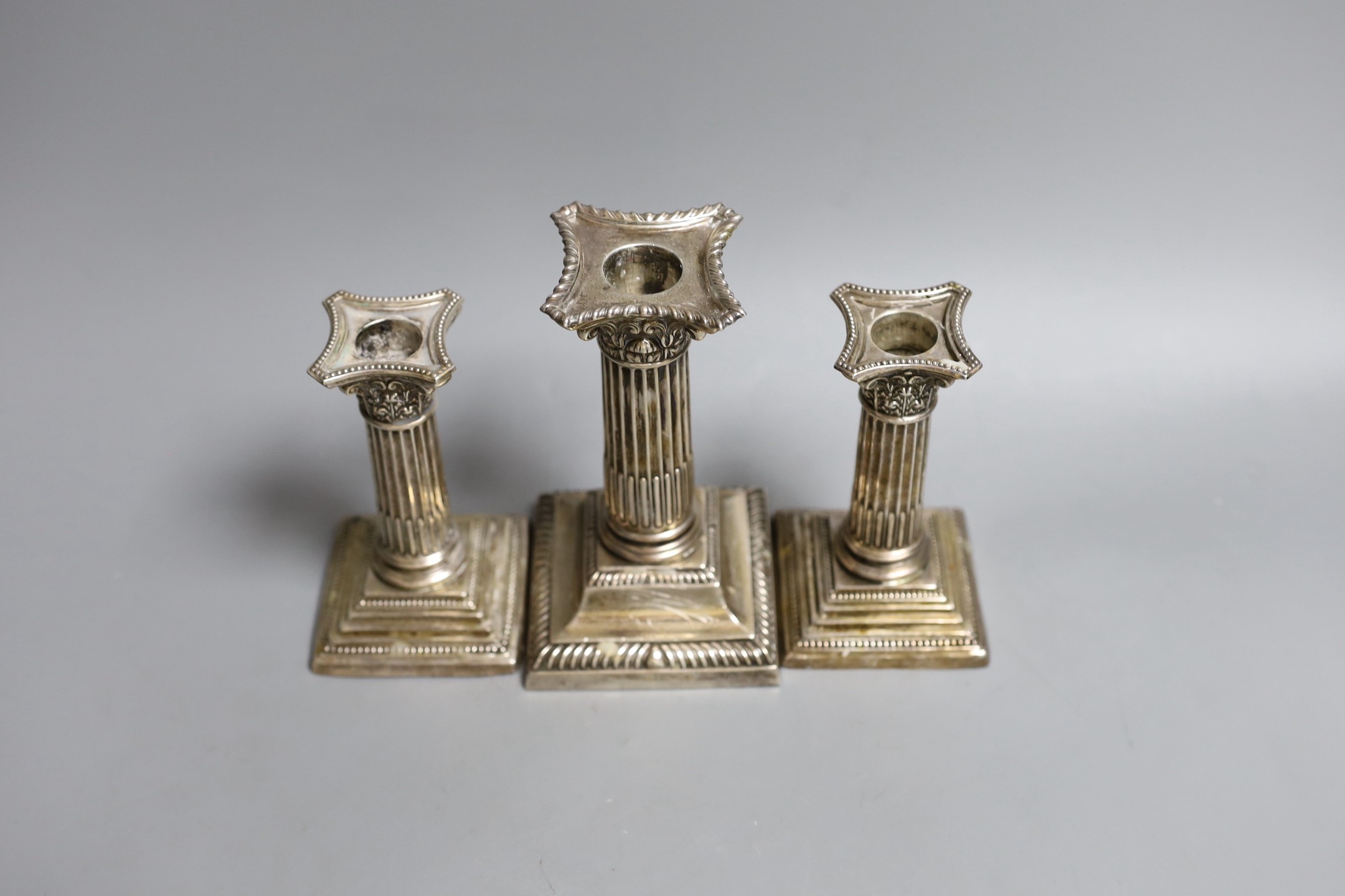 A pair of George V silver Corinthian column dwarf candlesticks, Cooper Brothers & Sons, Sheffield, 1911, 11.8cm, weighted and another similar larger candlestick.